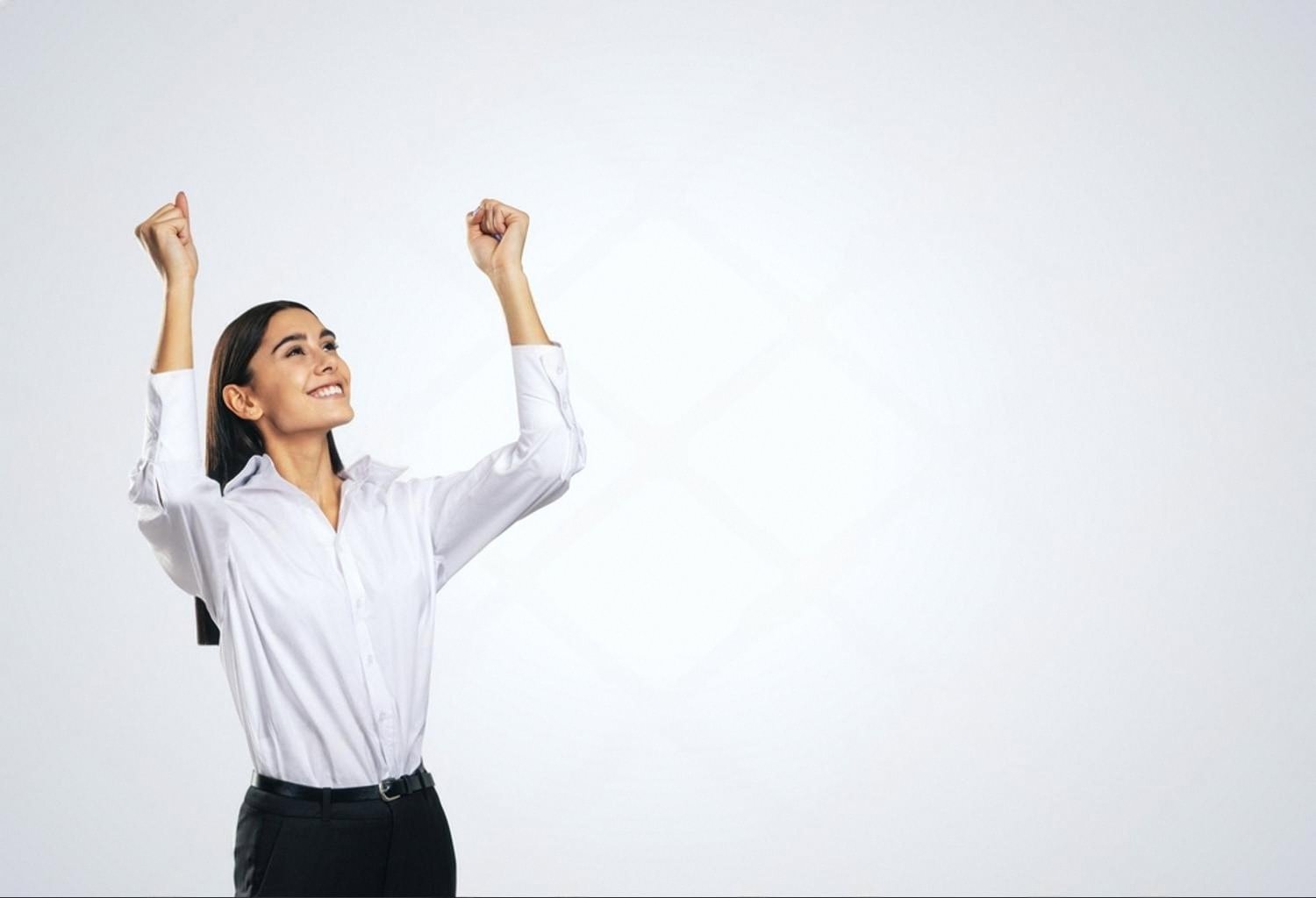 Smiling female leader with arms raised, celebrating a successful team outcome in a UAE workplace
